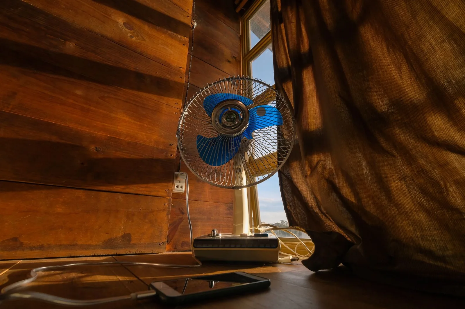 A fan by a window moving air through a room